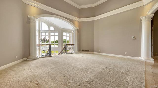 carpeted empty room featuring crown molding and ornate columns