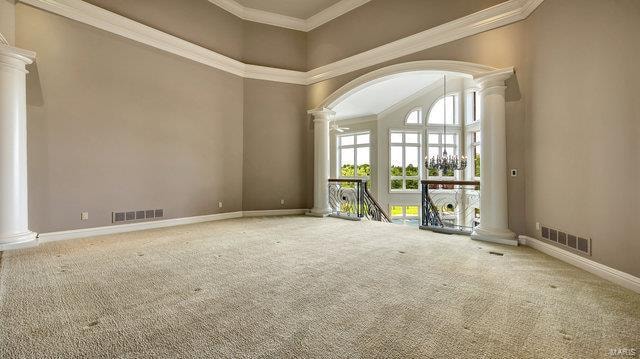 spare room with ornamental molding, carpet flooring, and decorative columns