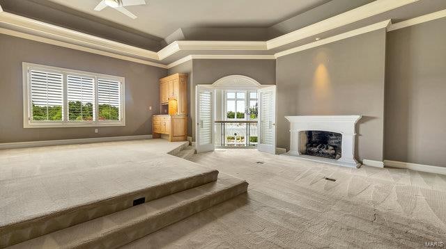 unfurnished living room with ceiling fan, crown molding, and light carpet