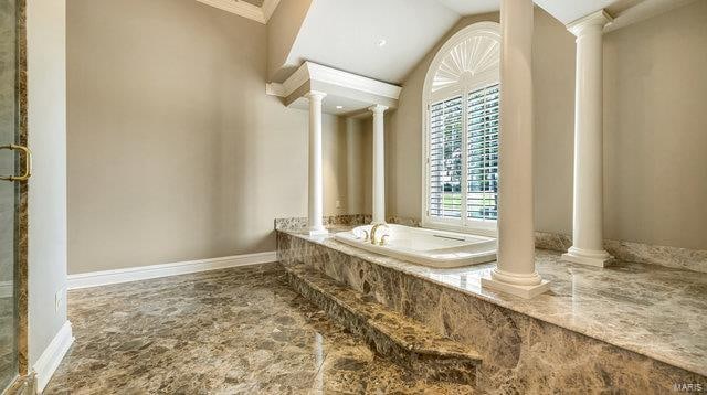 bathroom with decorative columns, tiled bath, crown molding, and vaulted ceiling