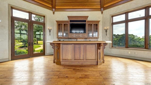 bar with a healthy amount of sunlight, a towering ceiling, and light hardwood / wood-style flooring