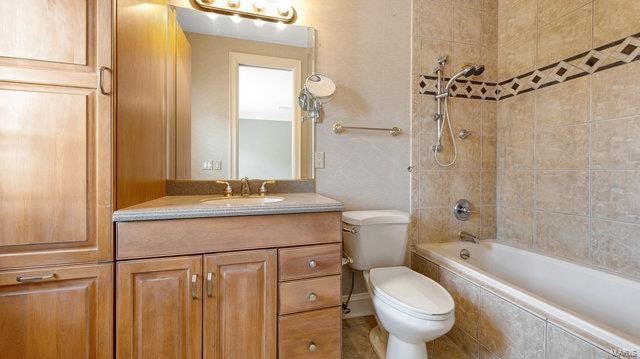 full bathroom with tiled shower / bath, vanity, and toilet