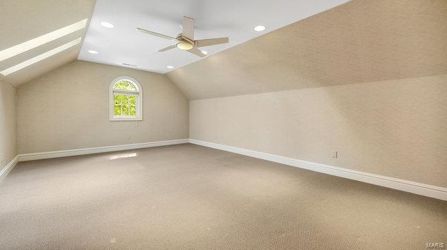 bonus room with carpet floors, vaulted ceiling with skylight, and ceiling fan