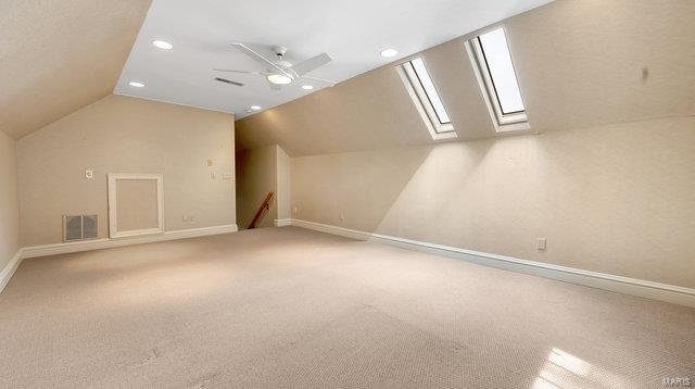 bonus room with ceiling fan, carpet, and vaulted ceiling with skylight