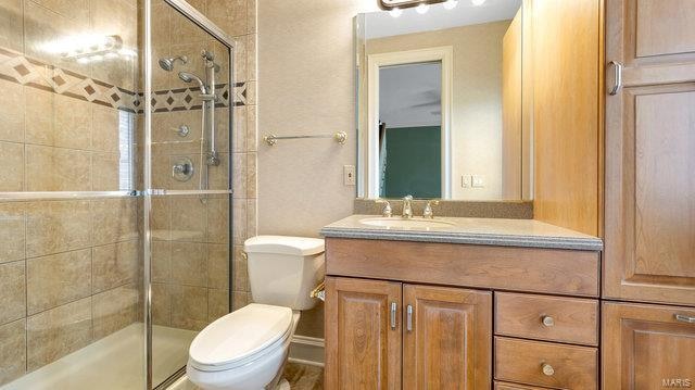 bathroom with a shower with shower door, vanity, and toilet