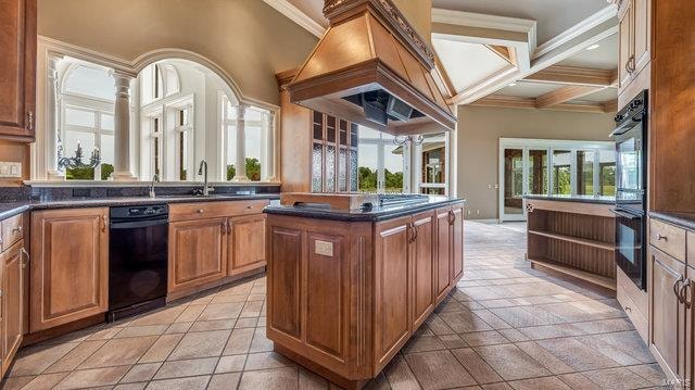 kitchen with beamed ceiling, a center island, sink, crown molding, and coffered ceiling