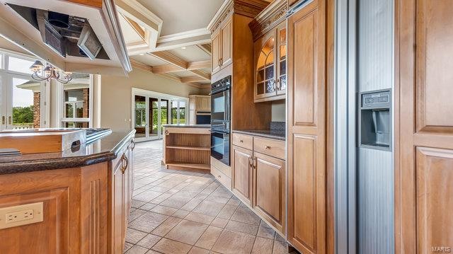 kitchen with coffered ceiling, beamed ceiling, black double oven, and a healthy amount of sunlight