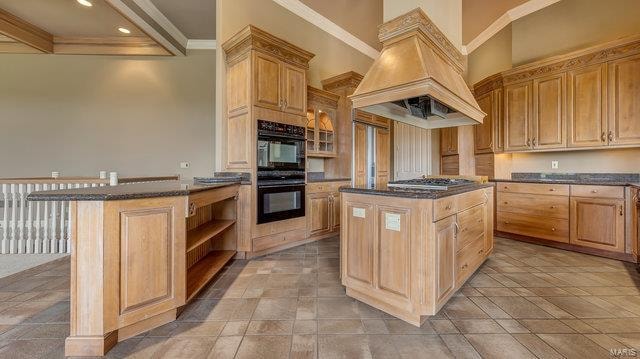 kitchen featuring black double oven, premium range hood, stainless steel gas stovetop, and a center island