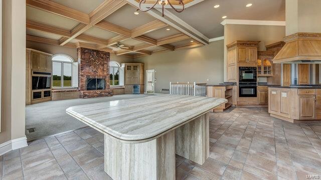 kitchen featuring custom range hood, beam ceiling, double oven, and a spacious island