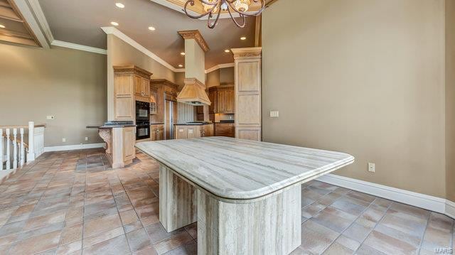 kitchen featuring a center island, a breakfast bar, a notable chandelier, crown molding, and light brown cabinetry