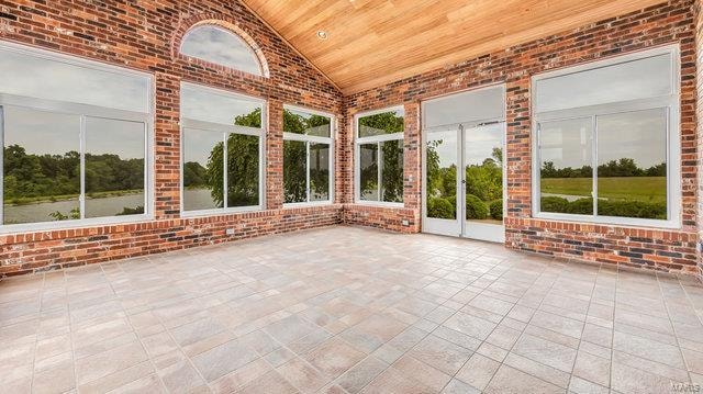 unfurnished sunroom featuring wood ceiling, plenty of natural light, and lofted ceiling