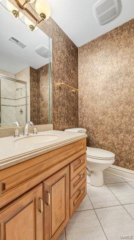 bathroom featuring tile patterned floors, toilet, vanity, and a shower with shower door