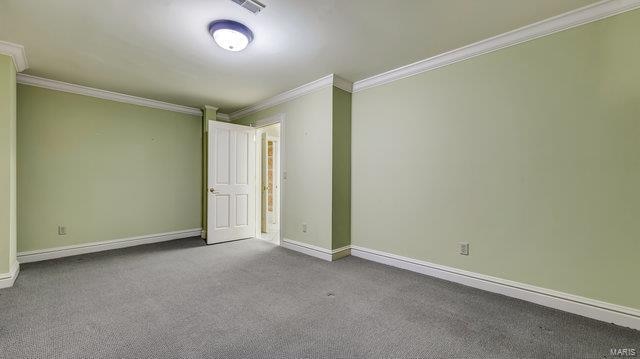 empty room with ornamental molding and light carpet