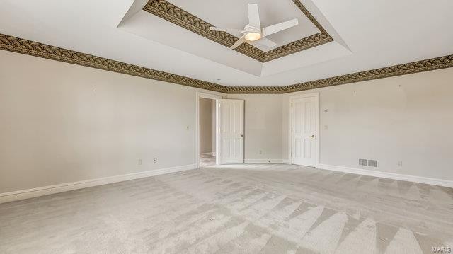 empty room featuring ceiling fan, carpet, and a raised ceiling