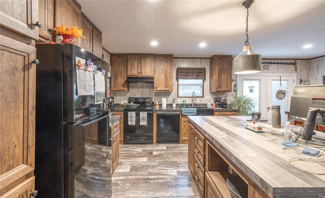 kitchen featuring pendant lighting, black appliances, sink, and wood counters