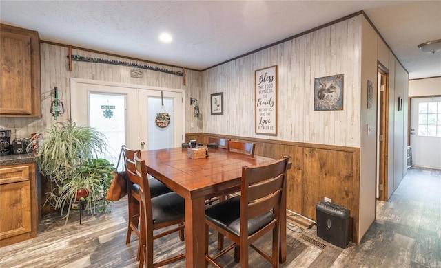 dining area with french doors, hardwood / wood-style flooring, wooden walls, and a textured ceiling