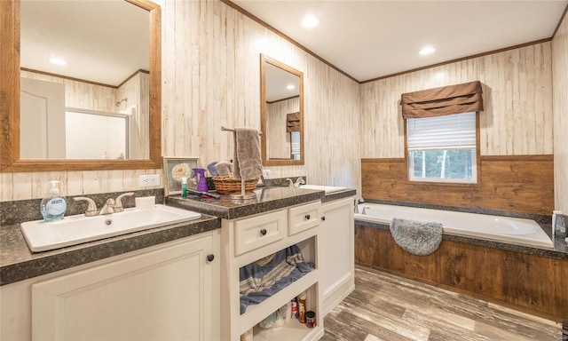 bathroom featuring wood walls, hardwood / wood-style floors, a tub to relax in, and vanity