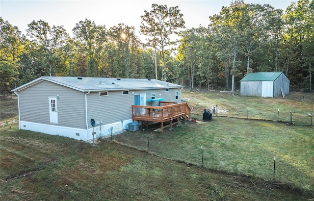 rear view of property featuring a yard, a wooden deck, a storage unit, and central air condition unit