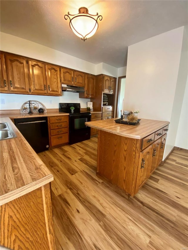 kitchen featuring light wood-type flooring, sink, wooden counters, and black appliances