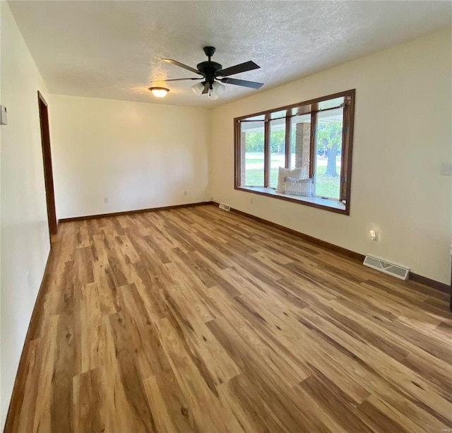 unfurnished room featuring light hardwood / wood-style floors, ceiling fan, and a textured ceiling