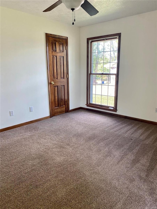 carpeted empty room with ceiling fan and a textured ceiling