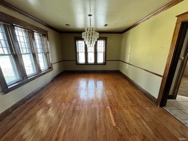 unfurnished dining area featuring ornamental molding, hardwood / wood-style flooring, and an inviting chandelier