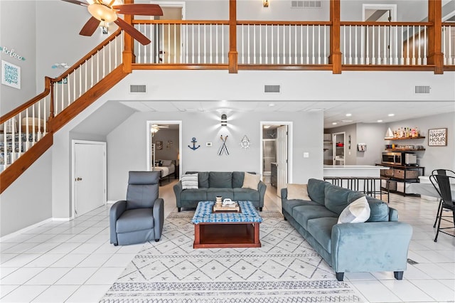 living room with a high ceiling, light tile patterned floors, and ceiling fan