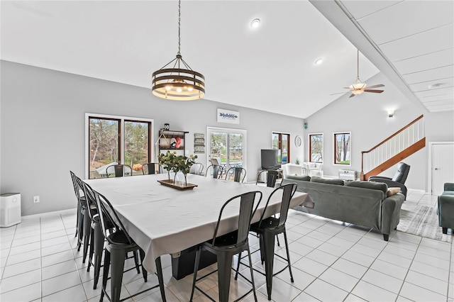 dining space with ceiling fan with notable chandelier, high vaulted ceiling, and light tile patterned flooring