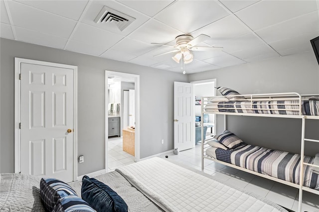 tiled bedroom featuring connected bathroom, ceiling fan, and a drop ceiling