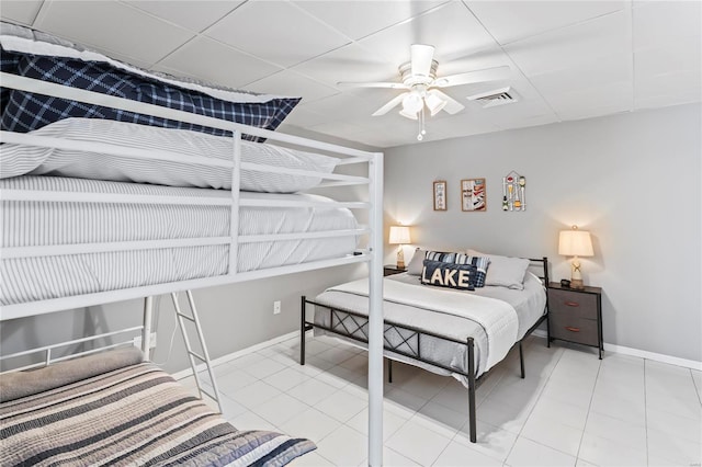 bedroom with a drop ceiling, ceiling fan, and light tile patterned floors