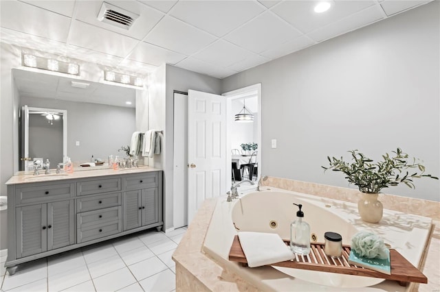 bathroom featuring tile patterned flooring, vanity, a relaxing tiled tub, and a paneled ceiling