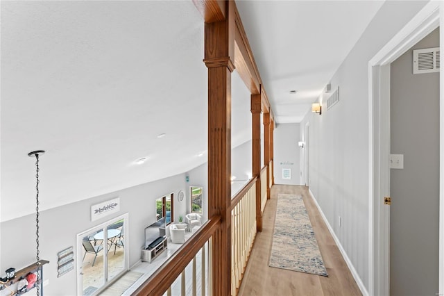 hall with vaulted ceiling and light hardwood / wood-style flooring