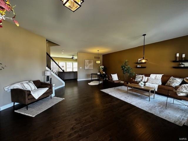 living room featuring baseboards, wood finished floors, and stairs