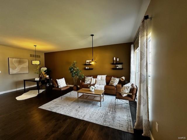 living room with visible vents, baseboards, and wood finished floors