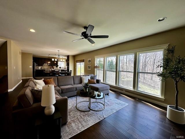 living room with recessed lighting, baseboards, dark wood-type flooring, and ceiling fan with notable chandelier