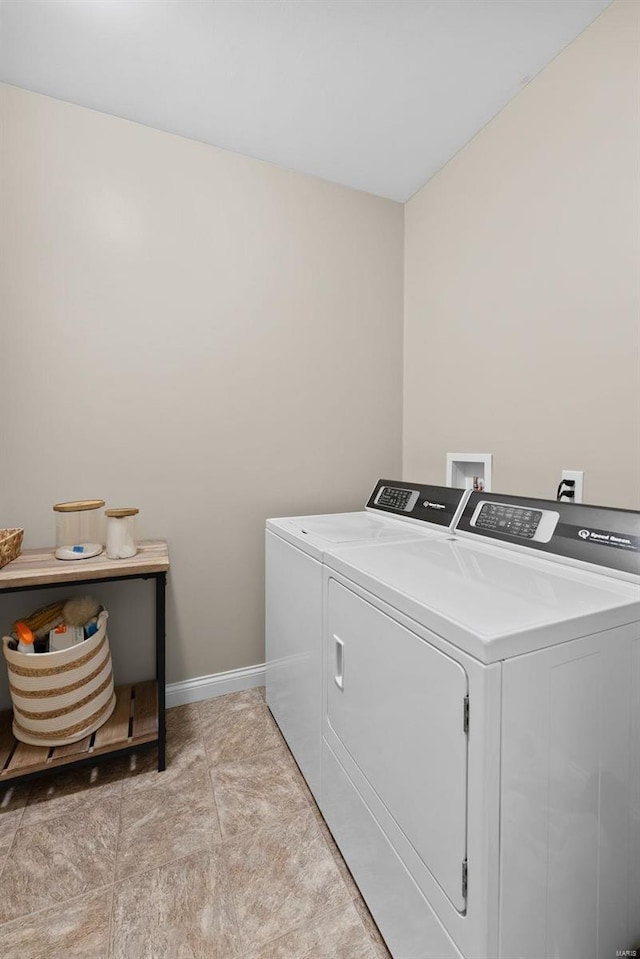 clothes washing area with baseboards, washing machine and dryer, and laundry area