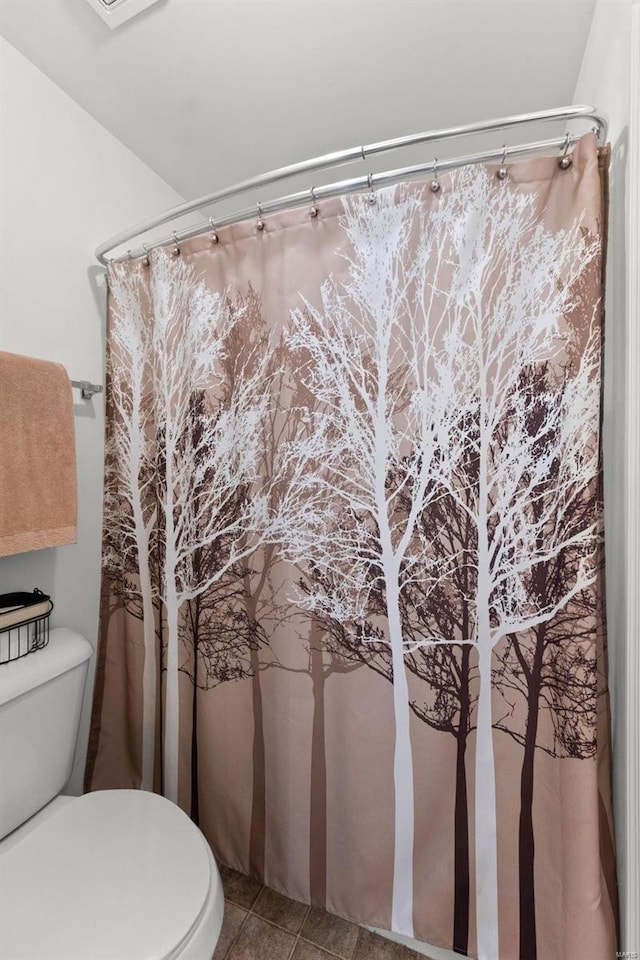 bathroom with a shower with shower curtain, tile patterned floors, and toilet