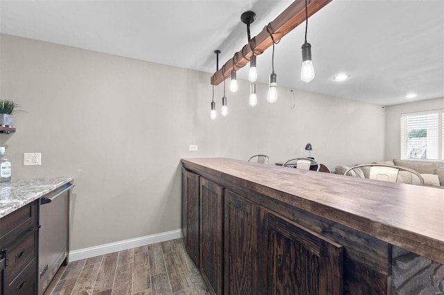 kitchen featuring dark brown cabinetry, wood finished floors, baseboards, and wood counters