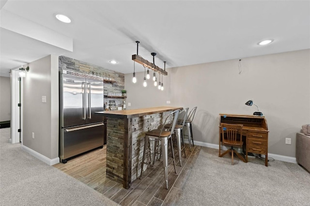 bar featuring a bar, baseboards, and stainless steel built in fridge