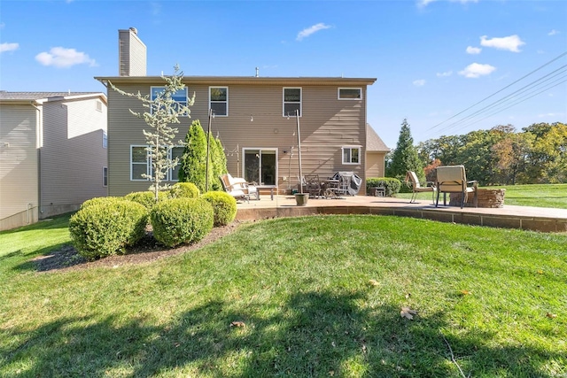 rear view of property featuring a yard, a patio, and a chimney