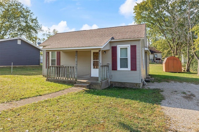 bungalow featuring covered porch, a storage shed, and a front yard