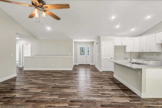 kitchen featuring light stone countertops, dark hardwood / wood-style floors, white cabinets, and vaulted ceiling