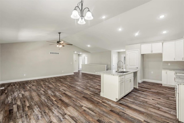 kitchen featuring white cabinets, lofted ceiling, sink, dark wood-type flooring, and light stone countertops