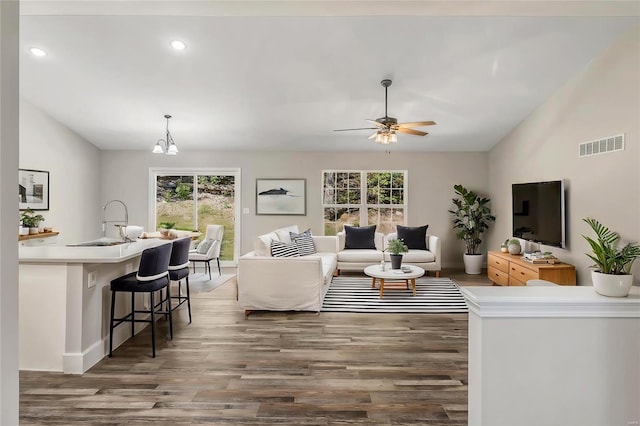 living room with ceiling fan with notable chandelier, plenty of natural light, dark hardwood / wood-style floors, and sink