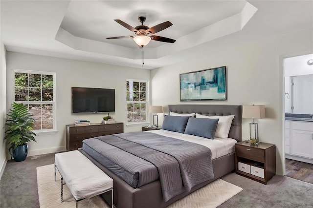 bedroom with ensuite bathroom, ceiling fan, hardwood / wood-style flooring, and a raised ceiling