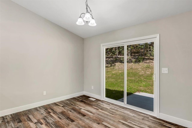 spare room with hardwood / wood-style floors and an inviting chandelier