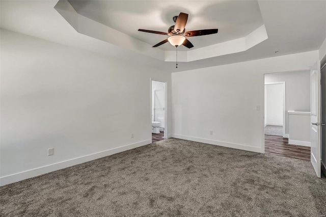 carpeted spare room with ceiling fan and a raised ceiling