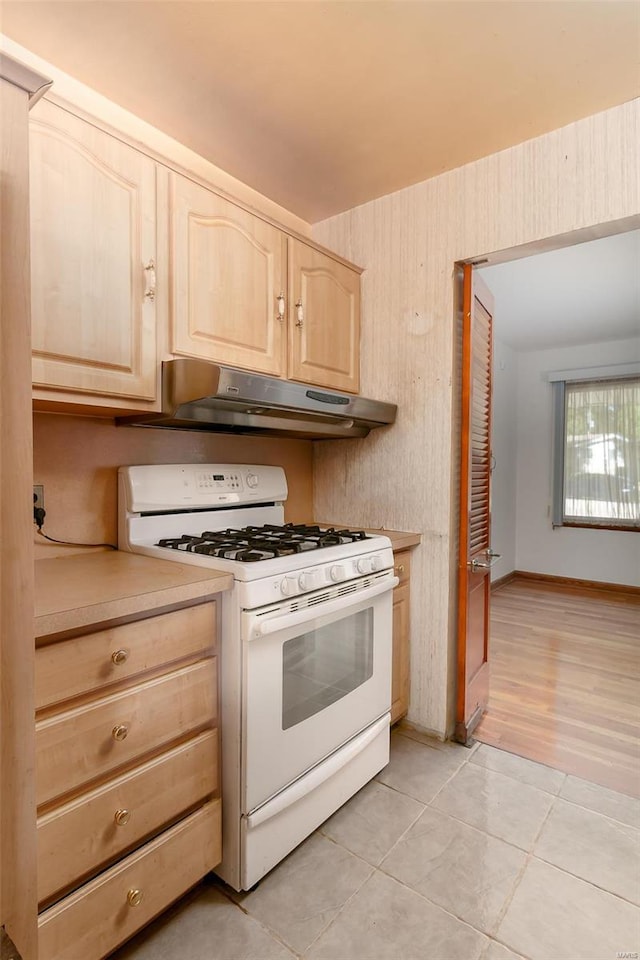 kitchen with light brown cabinetry, light wood-type flooring, and white gas range oven