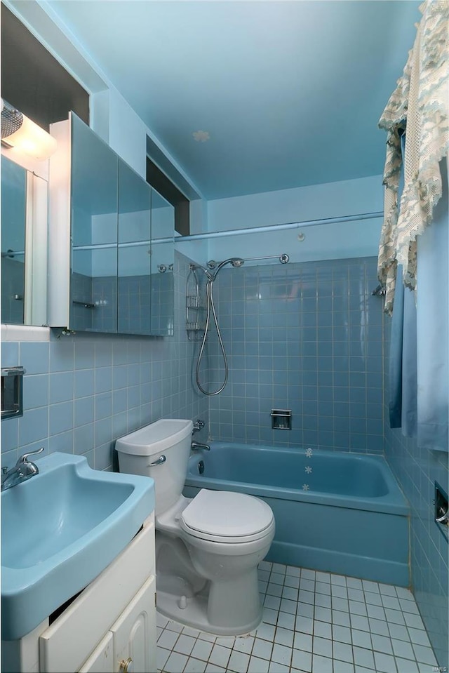 full bathroom with vanity, tasteful backsplash, tile walls, tiled shower / bath combo, and toilet