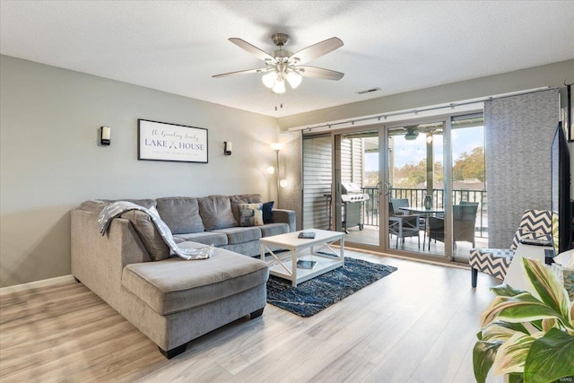 living room featuring ceiling fan, a textured ceiling, and light hardwood / wood-style floors